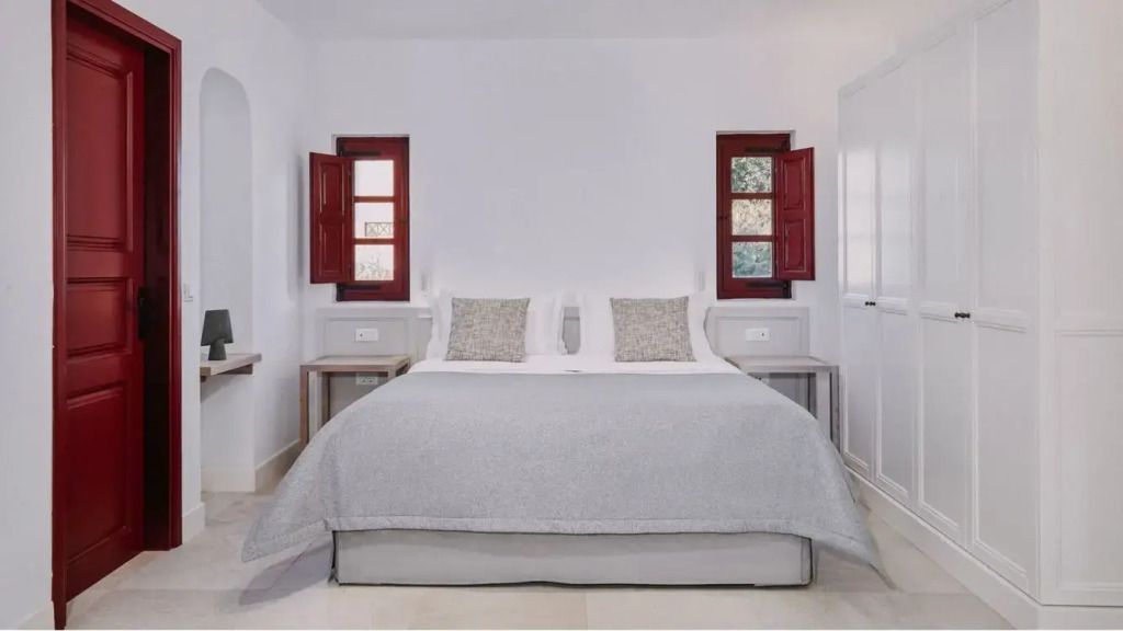 Doppelbett mit zwei Fenstern und minimalistischer Dekoration in der Dorian Suite