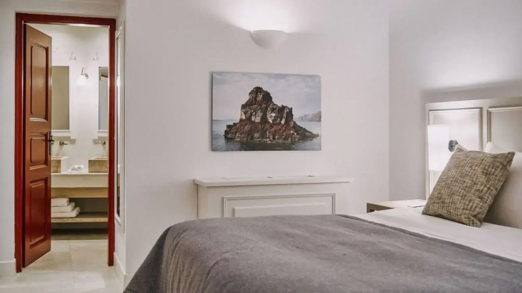 Minimalistisch eingerichtetes Zimmer mit Kunstwerk, das eine Felsformation über dem Meer zeigt