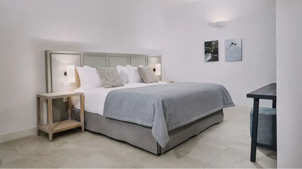 Helles Schlafzimmer mit Doppelbett und stilvollen Bildern an der Wand.