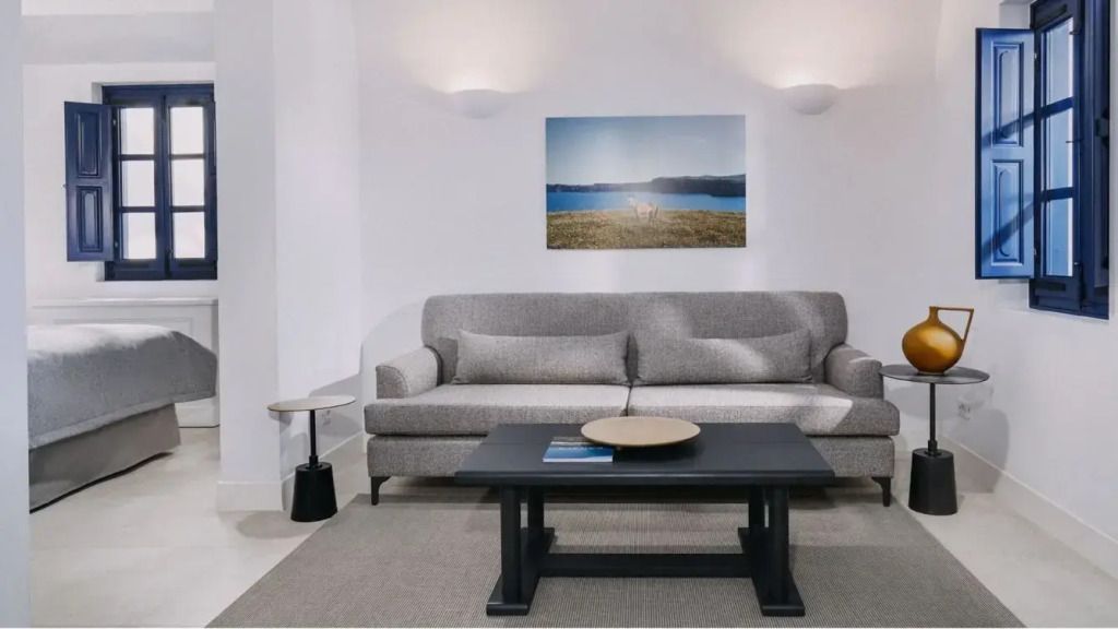Wohnbereich mit grauem Sofa und stilvollem Couchtisch in einer Suite.