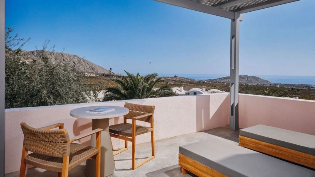 Terrasse mit Sitzbereich und Blick über Santorini-Landschaft und Meer.
