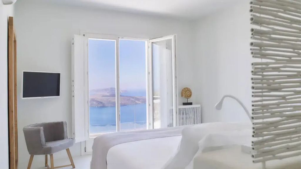 Helles Schlafzimmer mit Panoramablick auf das Meer durch große Fenster.