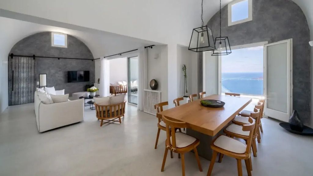 Essbereich mit Holztisch und Blick auf das Meer durch große Fenster.
