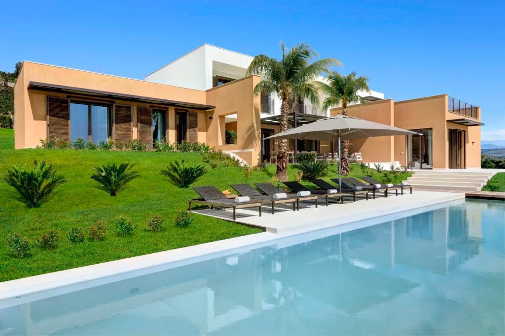 Außenansicht der Villa mit Pool und Liegestühlen im Garten.