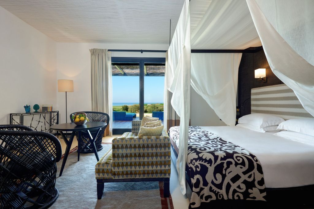 Geräumige Suite mit Himmelbett und Sitzbereich mit Meerblick