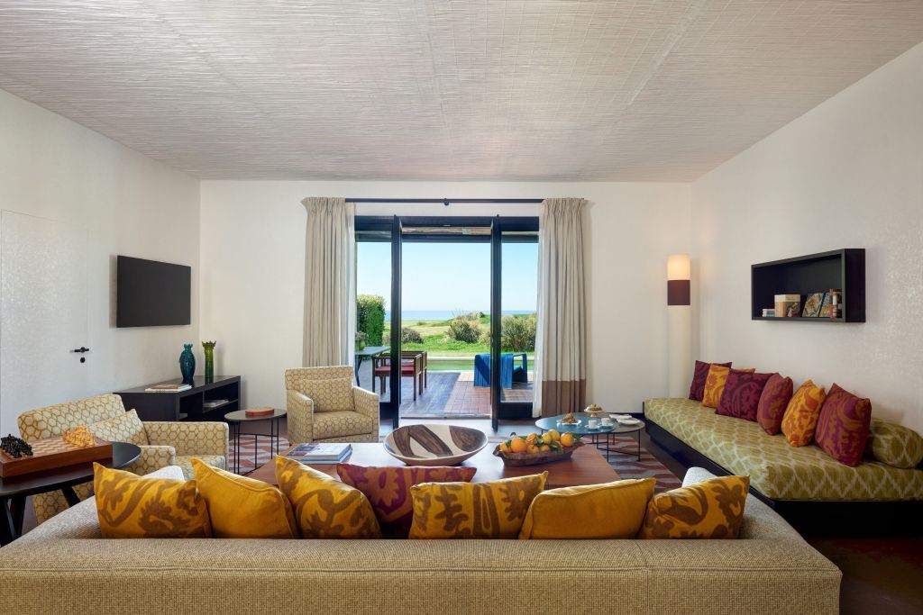 Helles Wohnzimmer einer Suite mit Zugang zur Terrasse und Meerblick