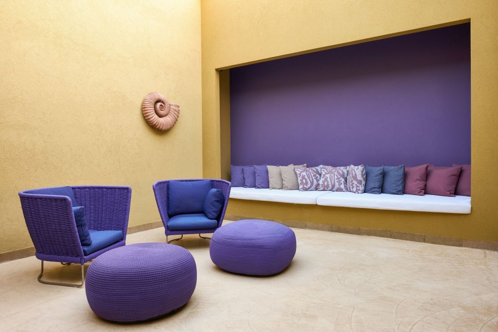 Überdachte Terrasse mit modernen, lila Möbeln und Wanddekoration