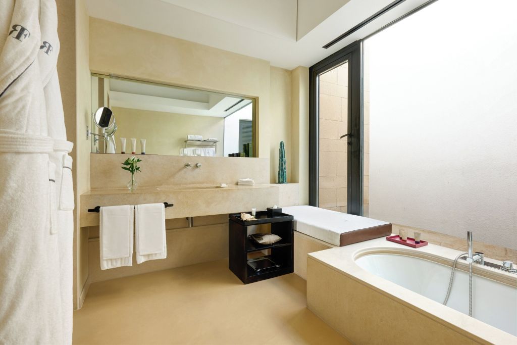 Helles Badezimmer im Verdura Resort mit großem Spiegel und Badewanne