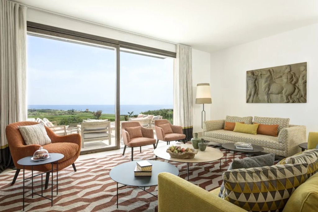 Wohnzimmer mit Meerblick in der Topazio Villa. Große Fensterfronten zum Garten.