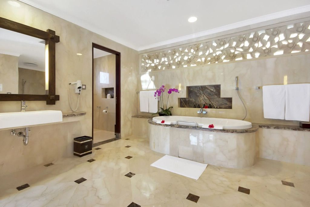 Helles Badezimmer mit Marmorverkleidung und eingelassener Badewanne.