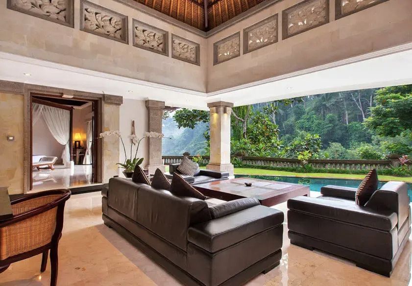 Wohnbereich mit Ledersofas und offener Aussicht auf Natur und Pool.