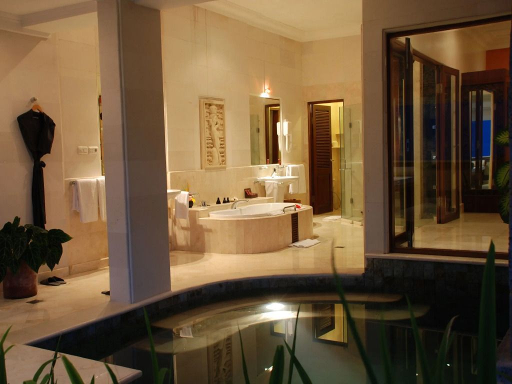 Opulentes Badezimmer mit eingelassener Badewanne, Marmoroberflächen und direktem Zugang zum Wasser.