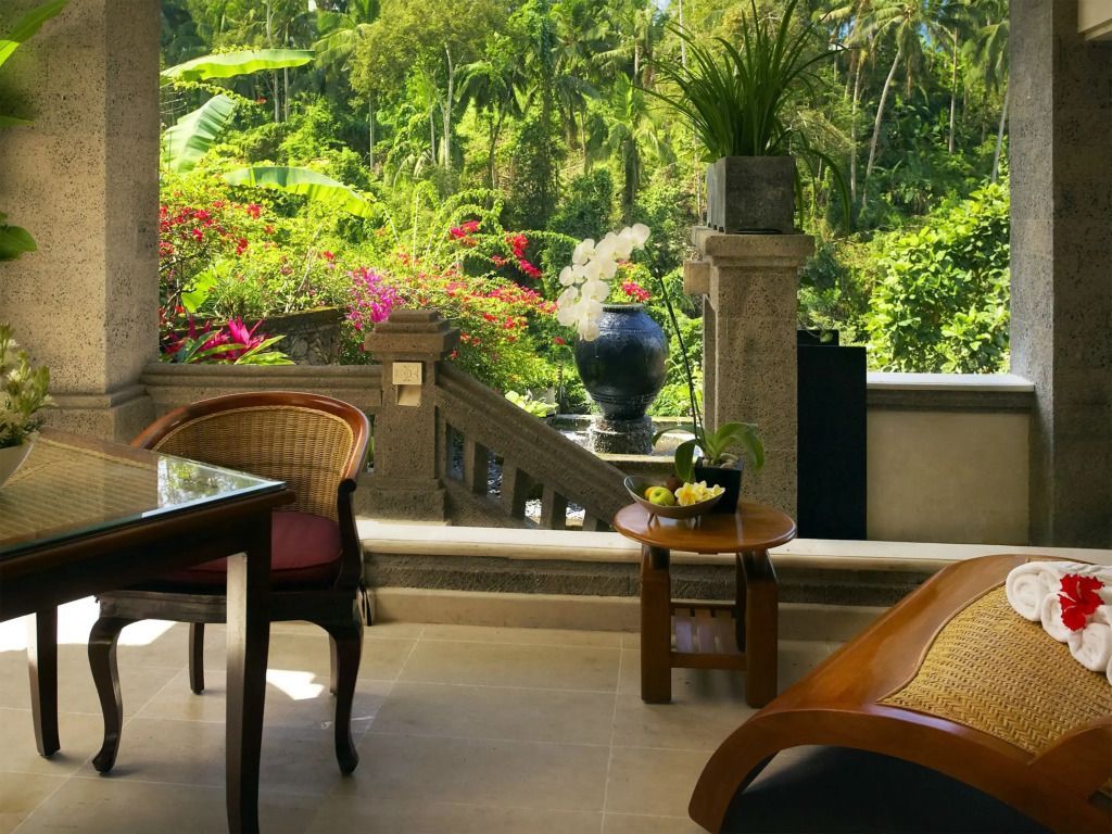 Terrasse mit Blick auf tropische Vegetation, Tisch mit Stühlen und Ruhebank.