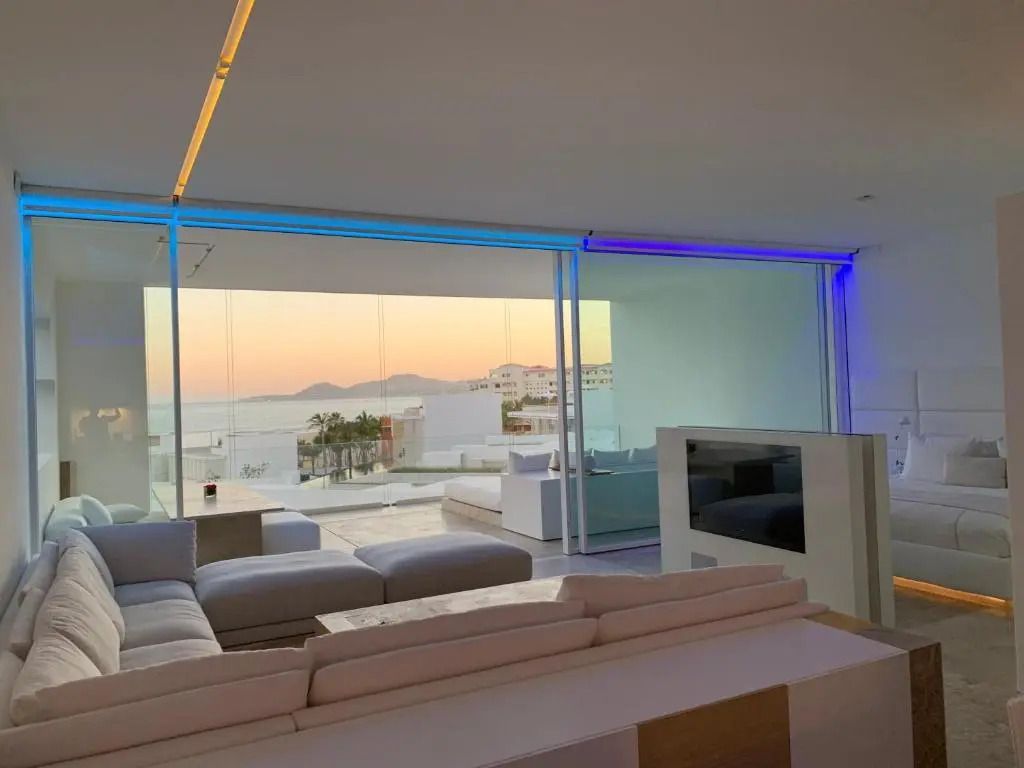 Wohnbereich eines Apartments mit Meerblick und elegantem Sofa bei Sonnenuntergang.