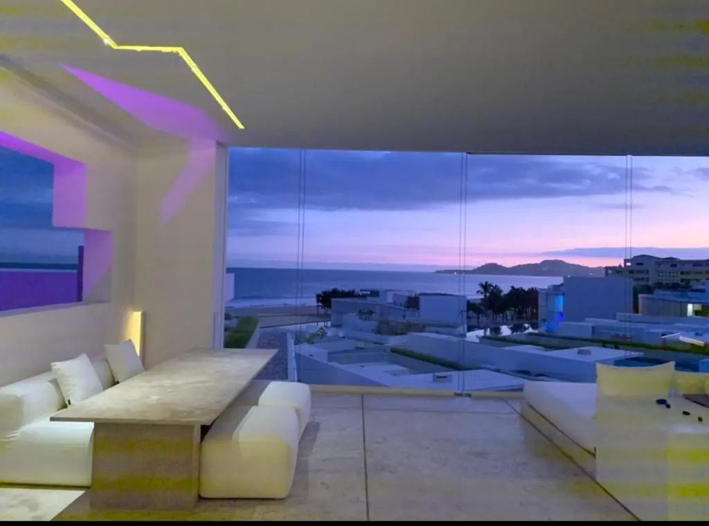 Wohnzimmer eines Apartments mit Blick auf das Meer bei Sonnenuntergang.