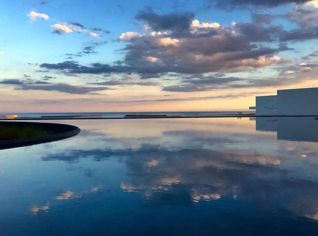 Infinity Pool reflektiert den Himmel bei Sonnenuntergang, spektakuläre Aussicht.