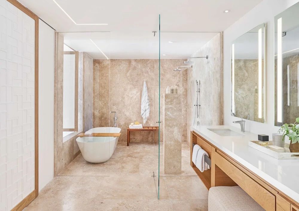 Luxuriöses Badezimmer mit freistehender Badewanne und Regendusche in edlem Marmor.