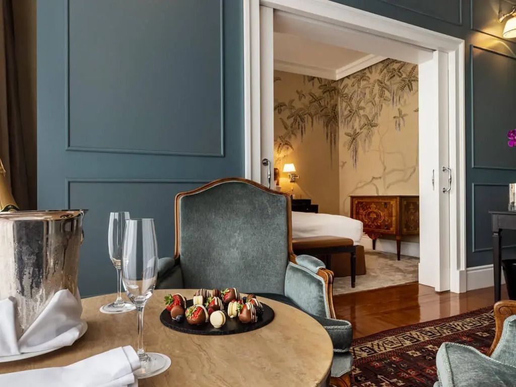 Sitzbereich mit Tisch und Champagner, im Hintergrund elegantes Schlafzimmer