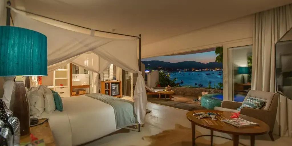 Deluxe Doppelzimmer mit Himmelbett und Meerblick bei Nacht.