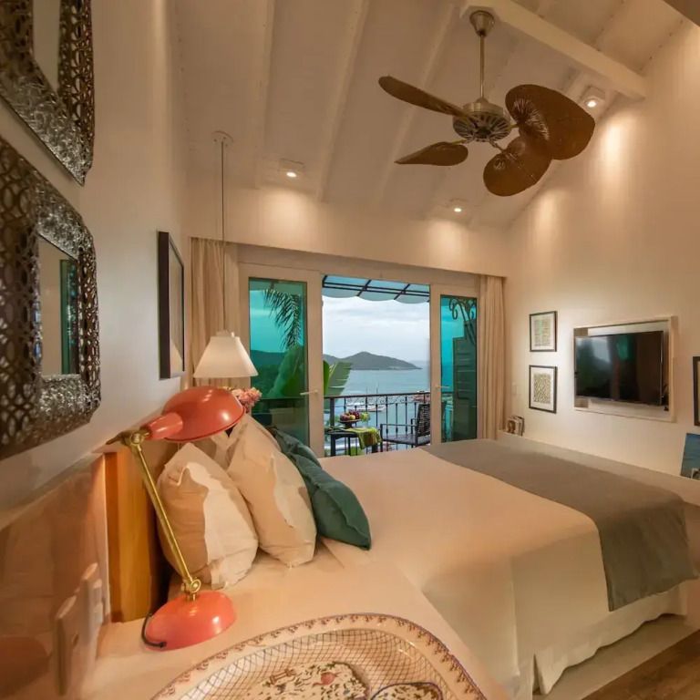 Gemütliches Schlafzimmer mit Balkonblick auf das Meer und eleganten Einrichtungselementen.