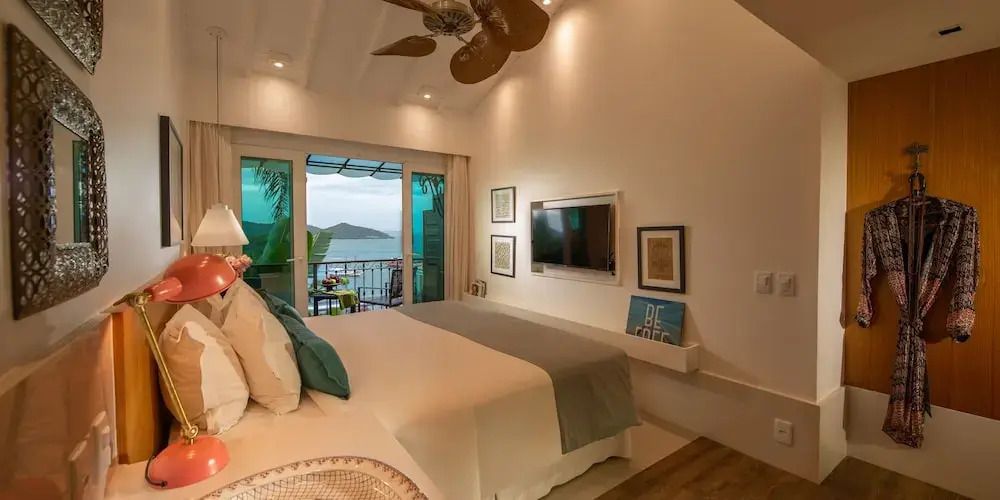 Schlafzimmer mit großem Bett und direktem Zugang zum Balkon mit Meerblick.