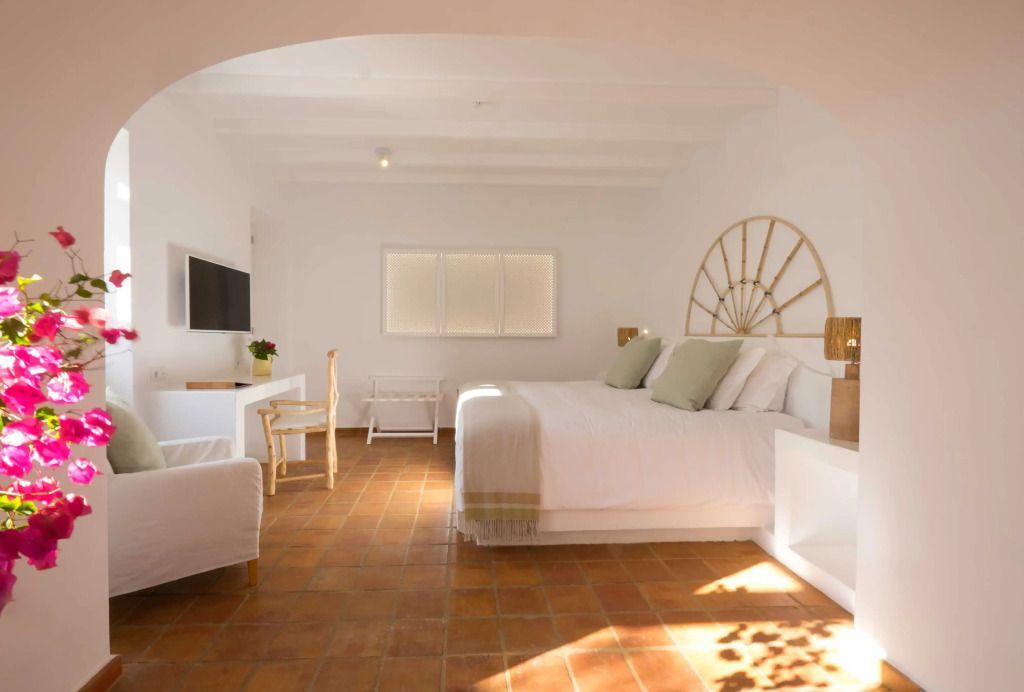 Geräumiges, helles Zimmer mit Doppelbett, weißen Wänden und Terrakottafliesen.
