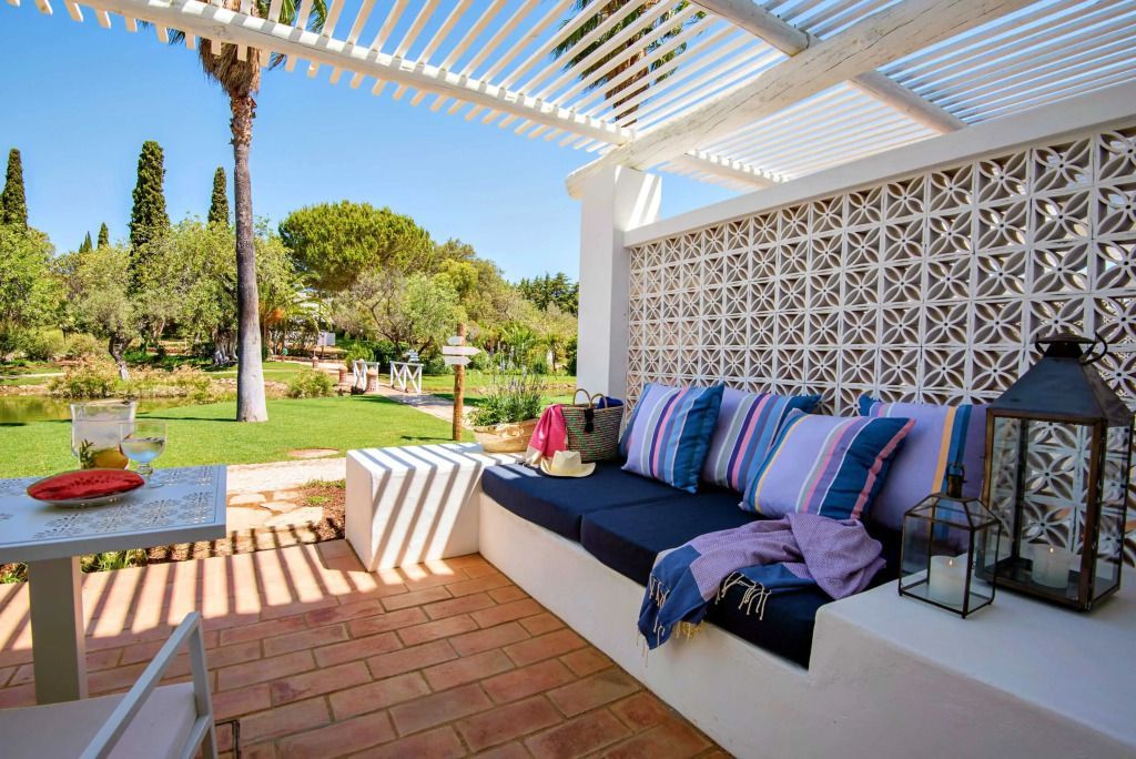Gemütliche Terrasse mit Sitzbereich, bunten Kissen und Blick auf grünen Garten.