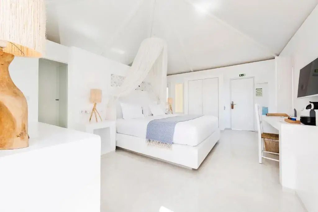 Helles Zimmer mit modernem Doppelbett, Himmelbett und weißen Akzenten.