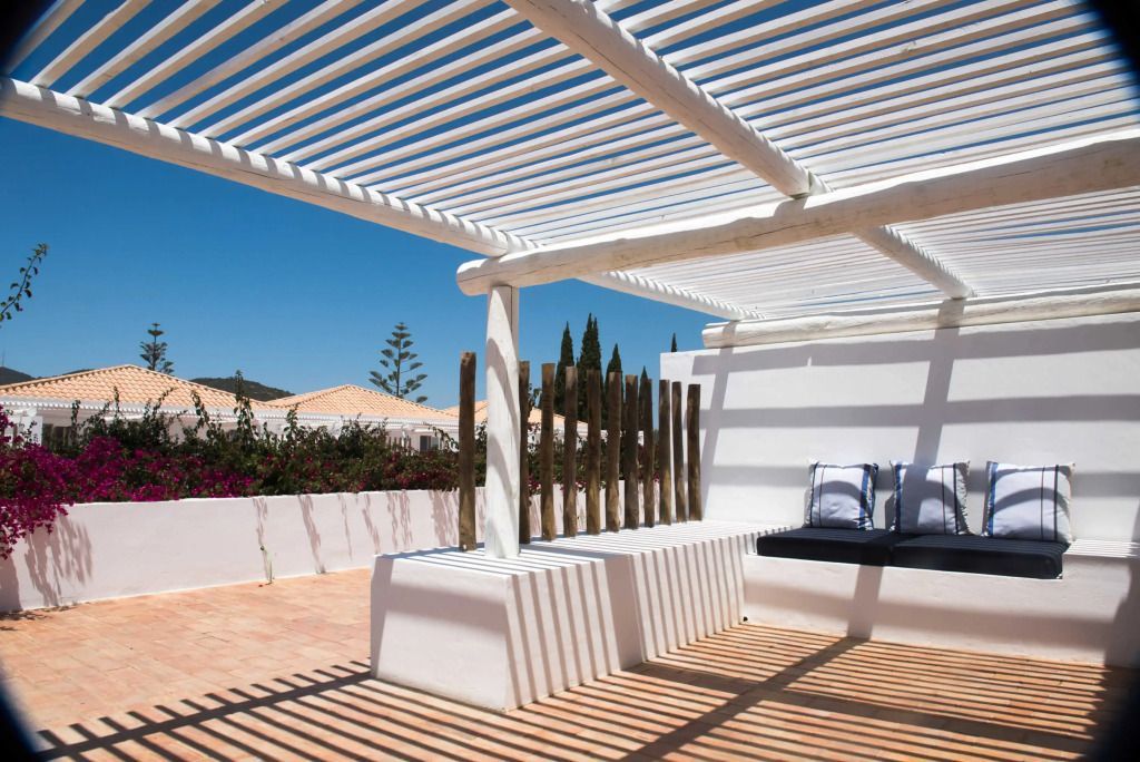 Terrasse mit modernem Sonnenschutz und Sitzbereich, umgeben von Natur.