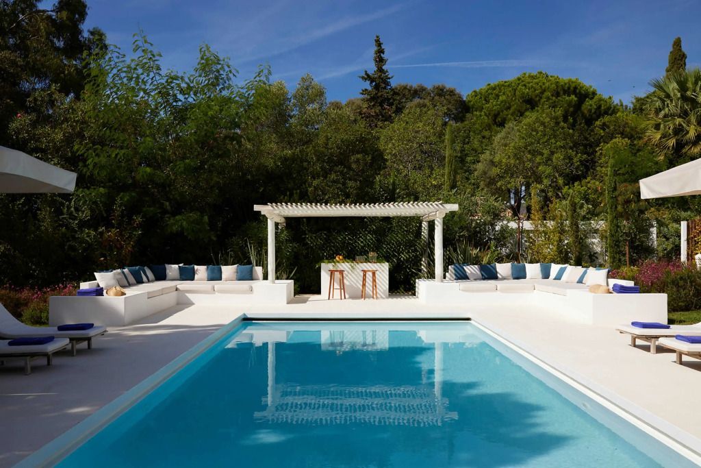Pool mit weißen Sitzbereichen und Pergola im Hintergrund