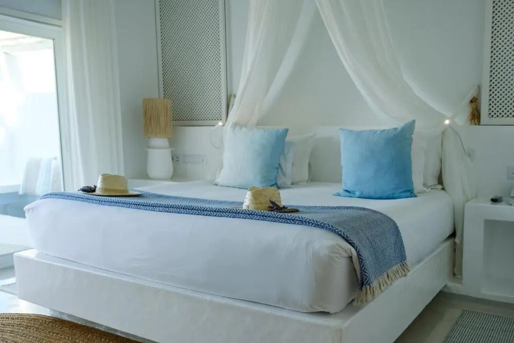 Gemütliches Bett in Superior Suite mit blauen Kissen und Baldachin