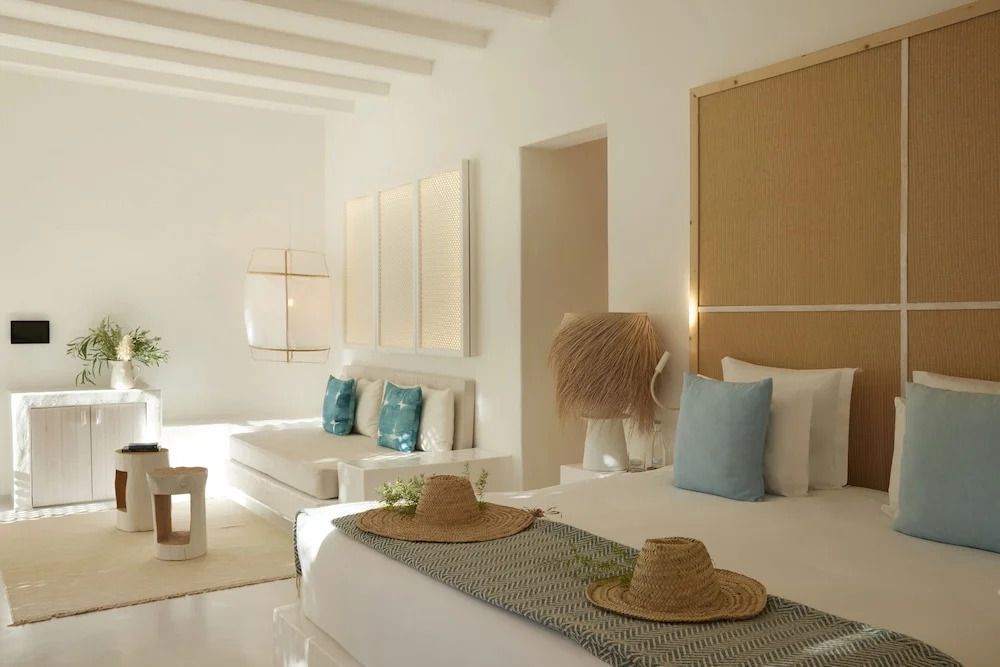 Elegantes Schlafzimmer in Villa mit zwei Sonnenhüten auf Bettdecke
