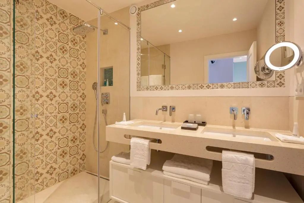 Modernes Badezimmer mit Doppelwaschbecken und kunstvoll gefliester Dusche.