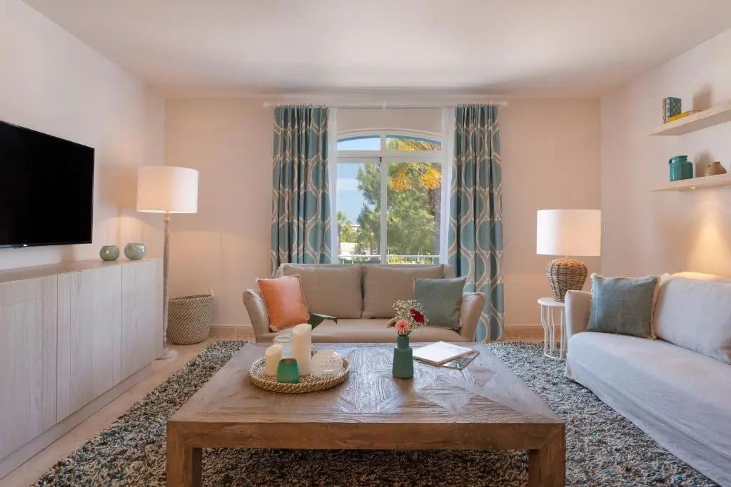 Wohnbereich mit stilvollen Sofas und großem Fenster mit Gartenblick.