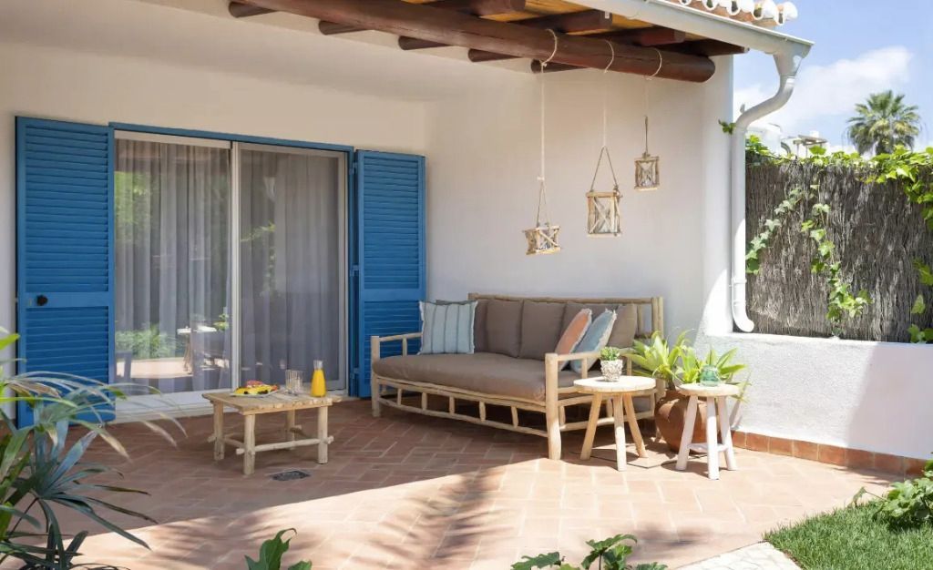 Terrasse mit Sitzgelegenheiten aus Holz unter Holzdach umgeben von Pflanzen