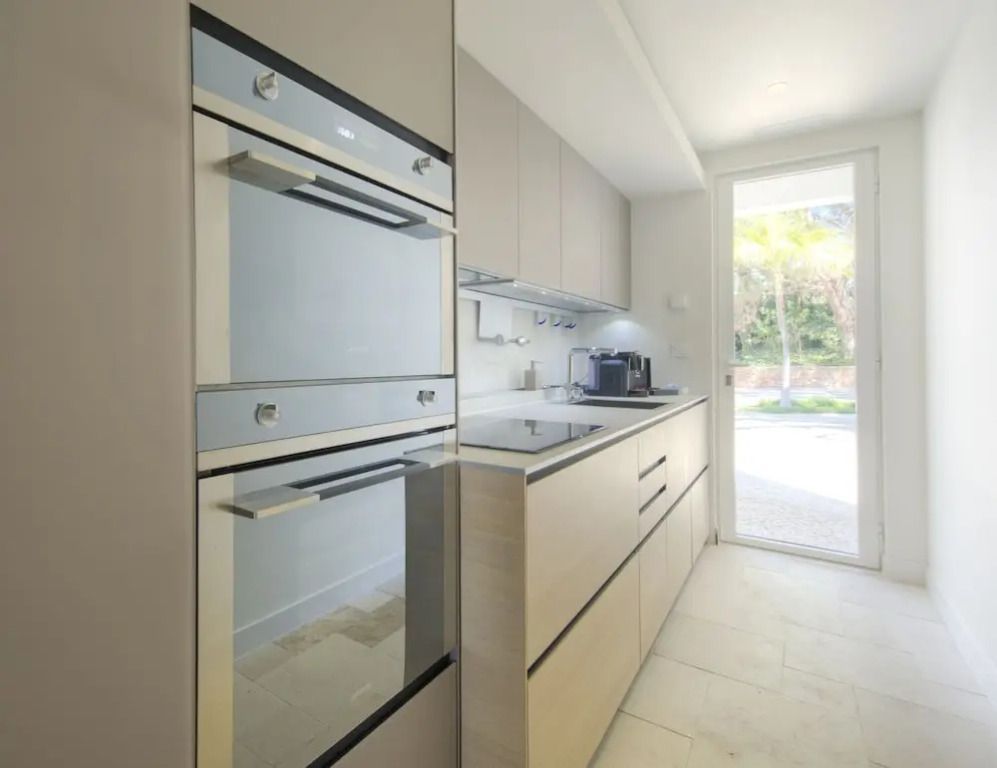 Moderne Küche mit Einbaugeräten und großem Fenster mit Gartenblick