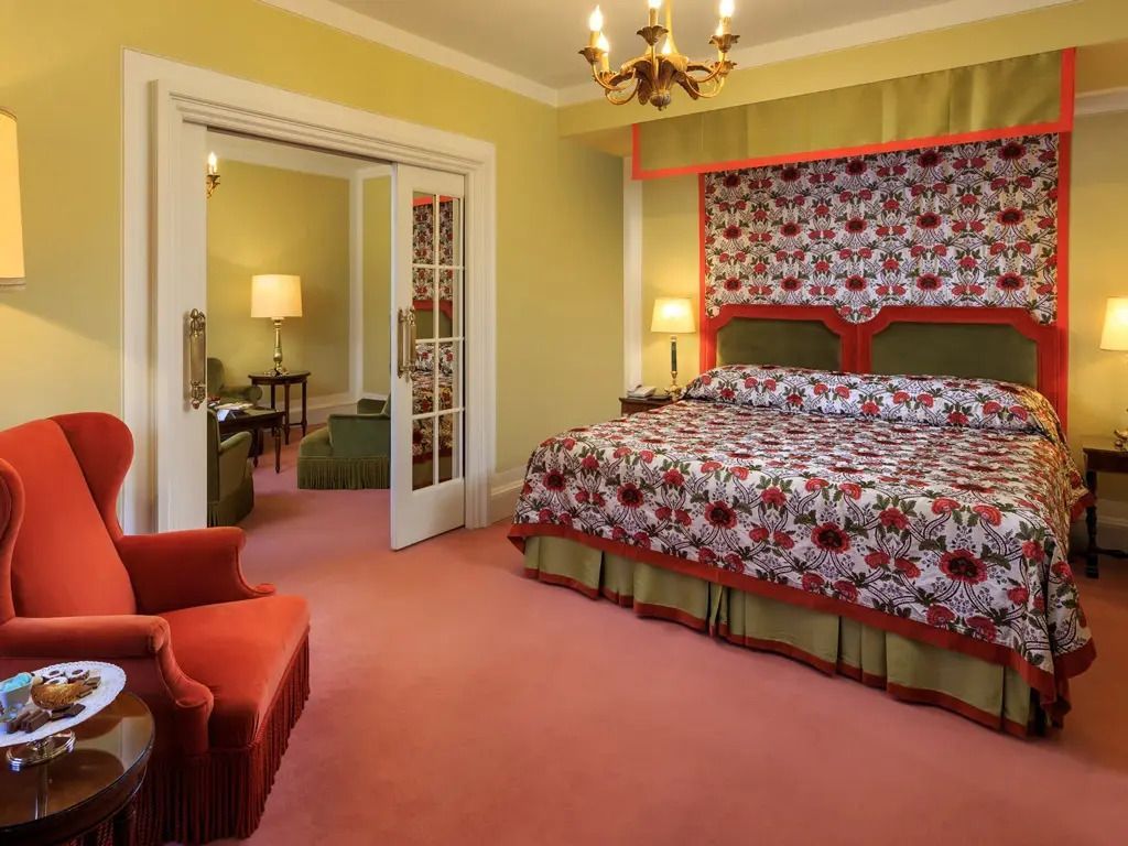 Elegantes Hotelzimmer mit floralem Bettbezug und Kronleuchter