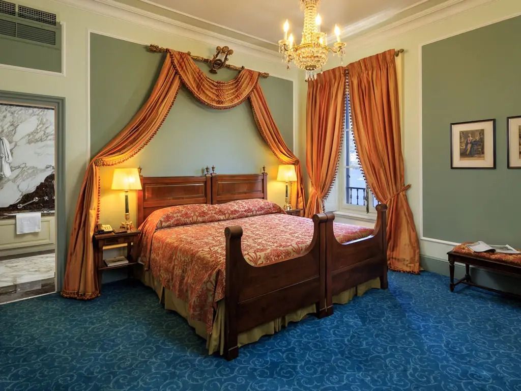 Elegantes Schlafzimmer mit Doppelbett und Kronleuchter in einer Suite mit Seeblick