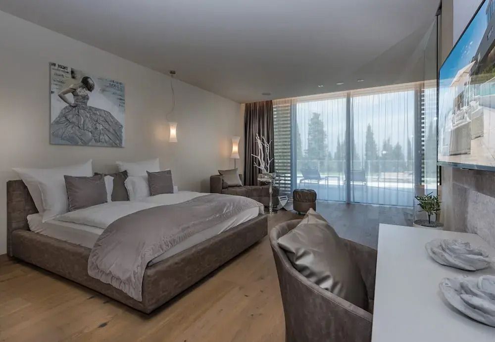 Modern eingerichtetes Hotelzimmer mit großem Doppelbett und Balkonzugang