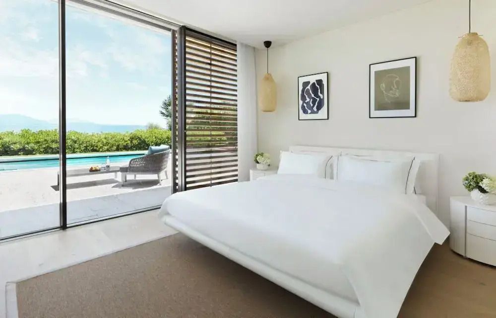 Modernes Hotelzimmer mit großem Bett und Blick auf privaten Pool