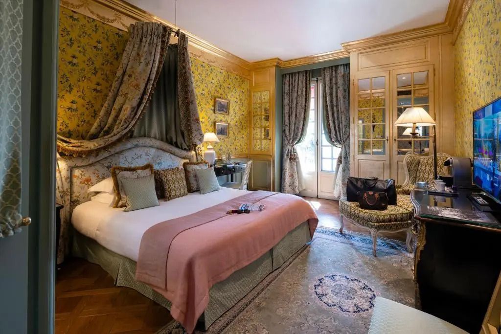 Geräumiges Deluxe Doppelzimmer mit elegantem Dekor, Stofftapeten und gemütlichem Bett.