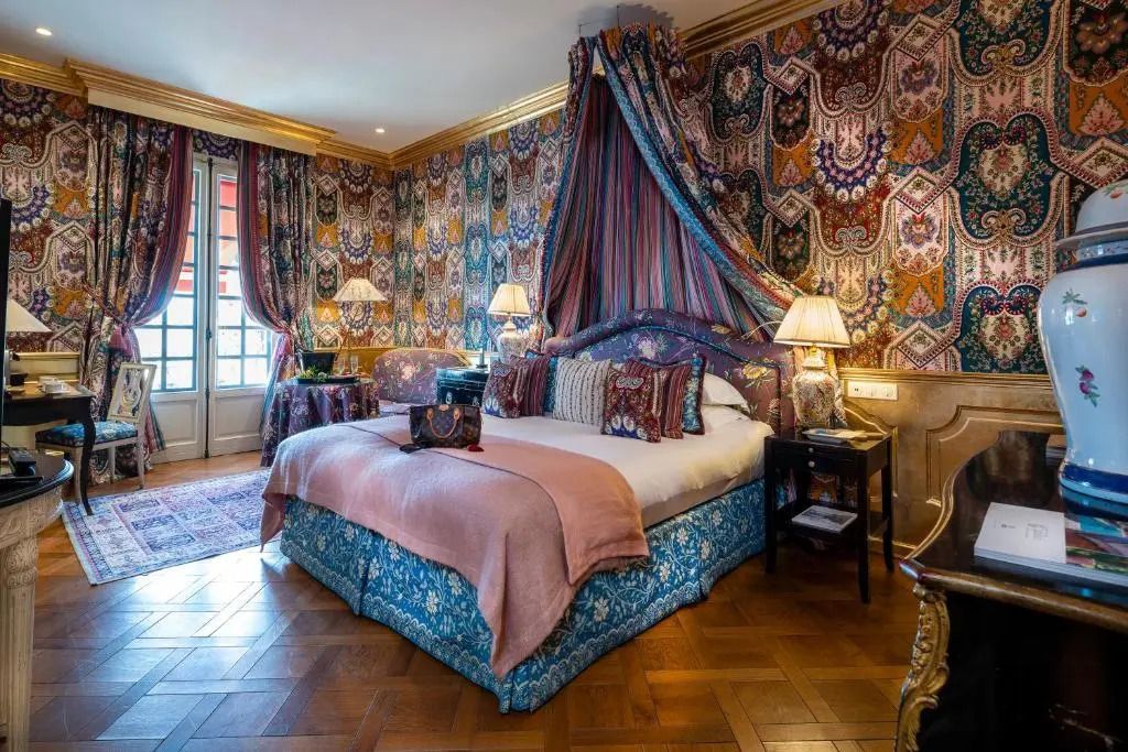 Luxuriös eingerichtetes Zimmer mit opulenter Bettwäsche und farbenfroher Wandgestaltung.