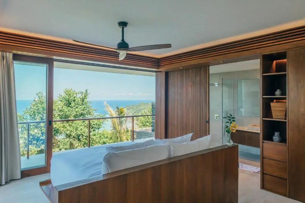 Schlafzimmer mit Blick auf tropische Vegetation und ferne Küste