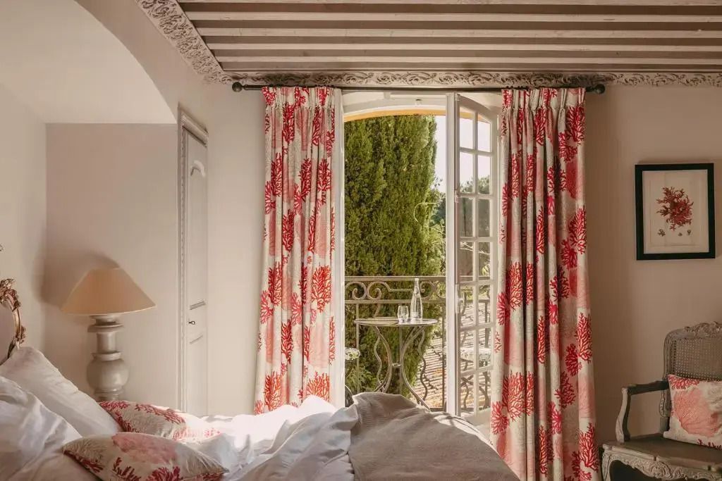 Charmante Schlafzimmerszene mit geöffneter Balkontür und floralem Vorhang im Hôtel Villa Marie Saint-Tropez
