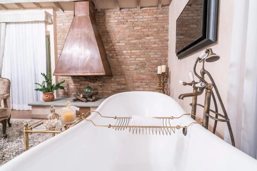Freistehende Badewanne mit eleganten Armaturen vor Backsteinwand
