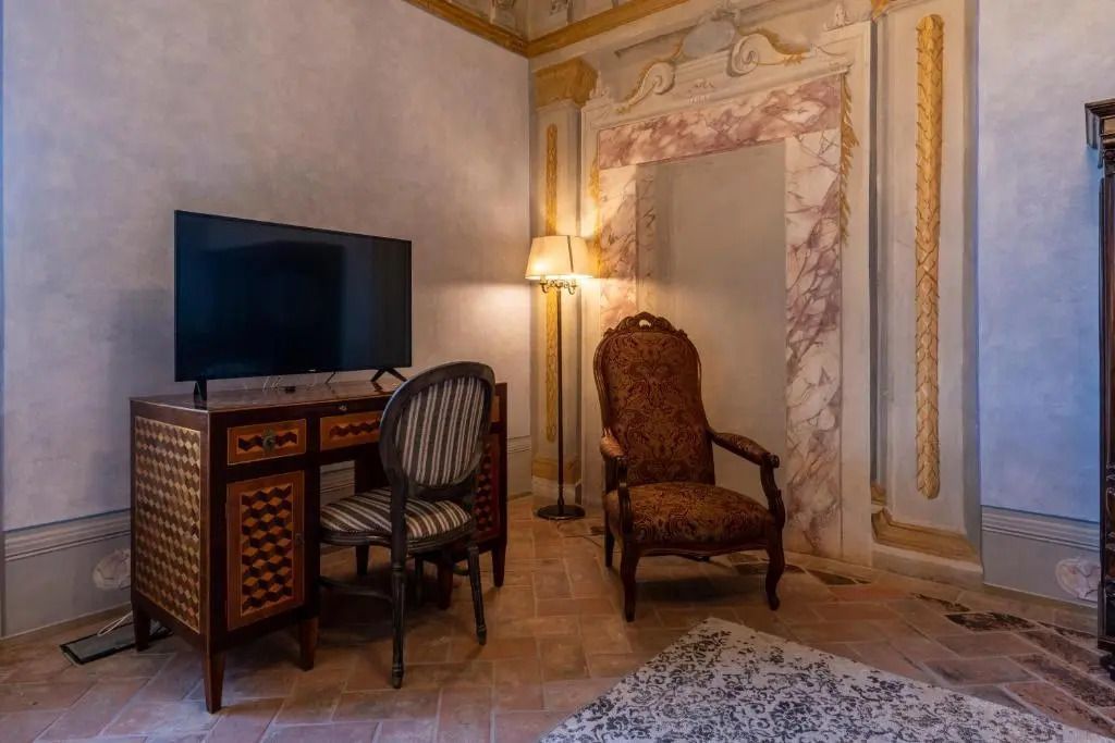 Schreibtisch und Sessel mit einem modernen Fernseher in der charmanten Suite
