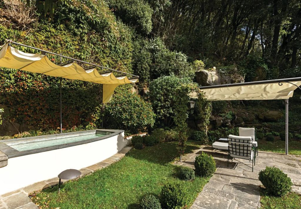 Gartenbereich mit Sitzgelegenheiten und kleinem Wasserbecken umgeben von üppigem Grün