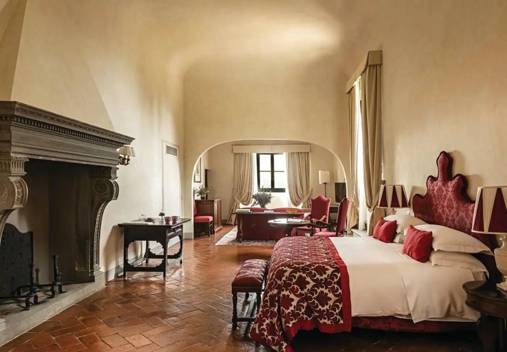 Elegante Michelangelo Suite mit Kamin, großen Fenstern und stilvollen Möbeln.