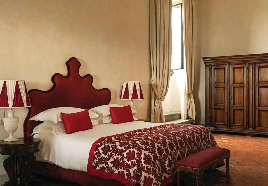 Luxuriöses Doppelbett in der Michelangelo Suite mit rotem Kopfteil und Vorhängen.