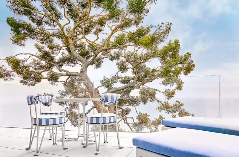 Terrasse mit blau-weißen Stühlen und Blick auf einen Baum